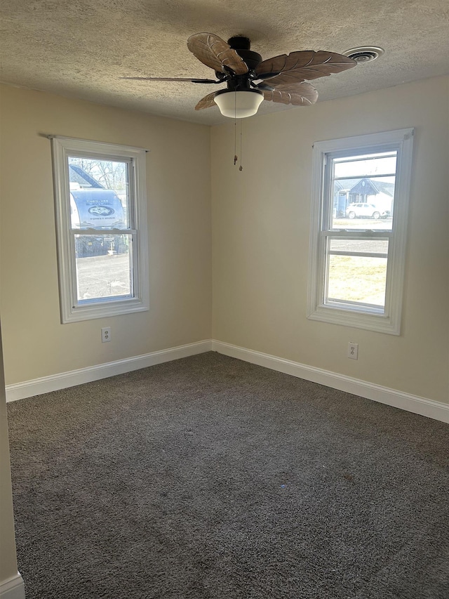 unfurnished room featuring visible vents, baseboards, ceiling fan, dark carpet, and a textured ceiling