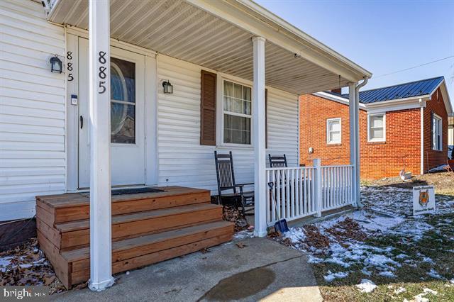 doorway to property with covered porch and brick siding