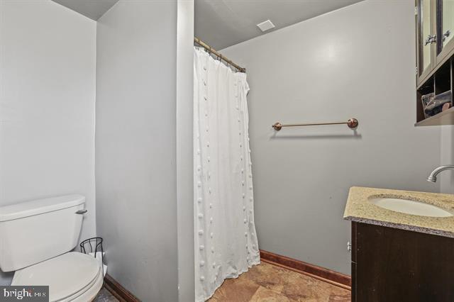 full bath with toilet, a shower with curtain, baseboards, and vanity