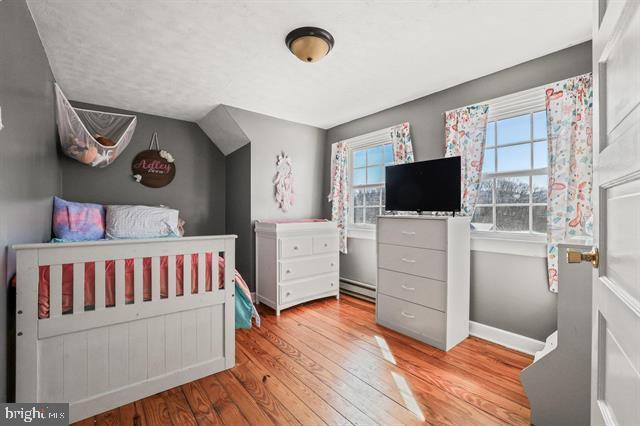 bedroom featuring a baseboard radiator, wood finished floors, and baseboards