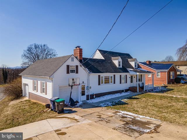 exterior space with a front yard, concrete driveway, a chimney, and an attached garage