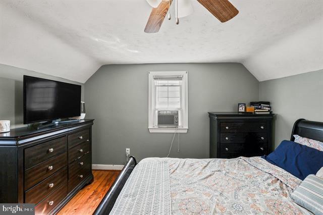 bedroom featuring lofted ceiling, a ceiling fan, baseboards, and wood finished floors