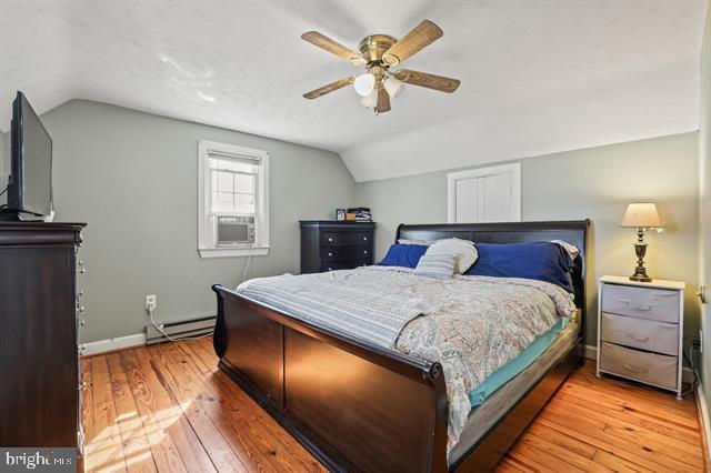 bedroom featuring ceiling fan, hardwood / wood-style flooring, baseboards, vaulted ceiling, and baseboard heating