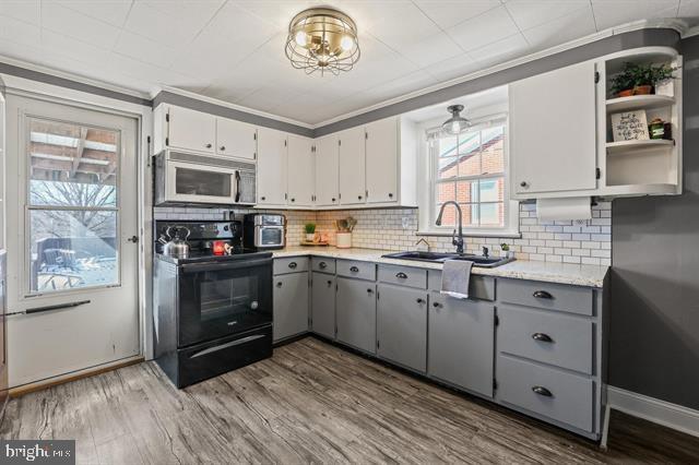 kitchen featuring a sink, white microwave, gray cabinets, and black / electric stove