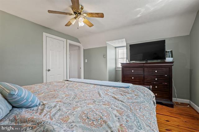 bedroom featuring vaulted ceiling, wood finished floors, a ceiling fan, and baseboards