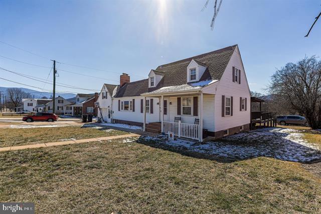 cape cod home with a front yard, covered porch, and a residential view