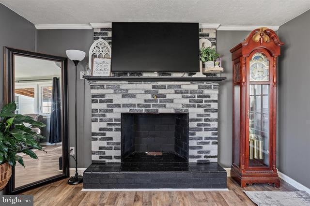 interior details featuring crown molding, a fireplace, and wood finished floors