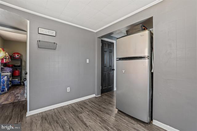 empty room with ornamental molding, baseboards, and wood finished floors