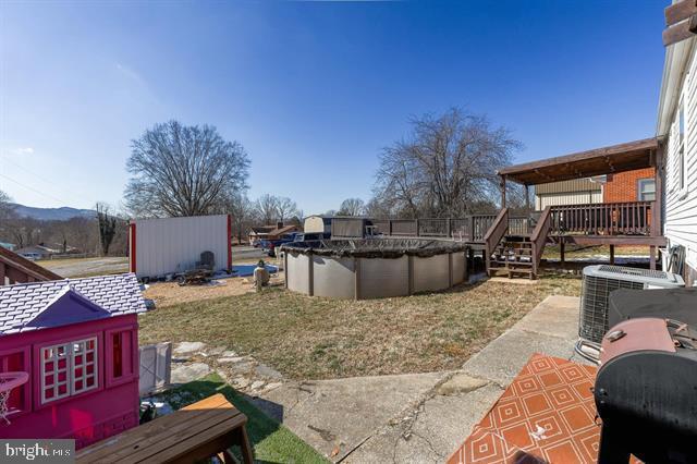 view of yard with a deck, central AC unit, and a covered pool