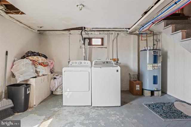 washroom with laundry area, electric water heater, and washing machine and clothes dryer