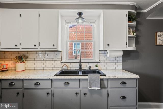 kitchen featuring white cabinets, decorative backsplash, gray cabinetry, open shelves, and a sink