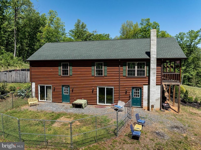 rear view of property with a lawn, a chimney, a fenced backyard, and faux log siding