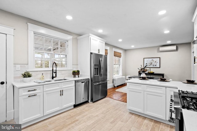 kitchen with appliances with stainless steel finishes, radiator, sink, and white cabinets