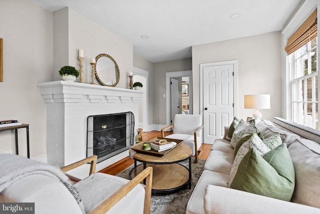 living room with wood-type flooring and a brick fireplace