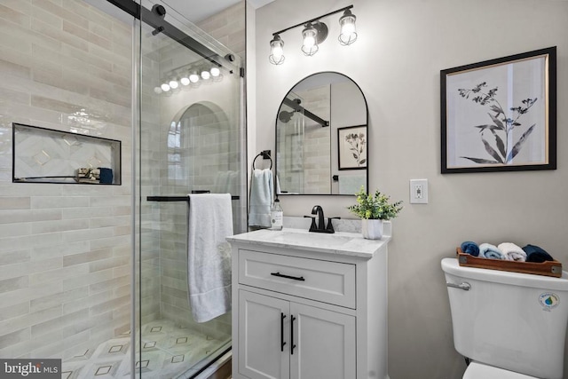 bathroom featuring vanity, toilet, and a shower with door