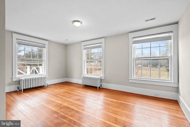 empty room with hardwood / wood-style flooring and radiator heating unit