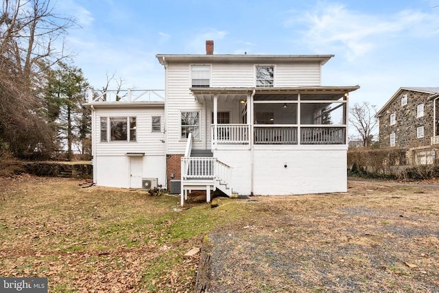 rear view of house featuring a sunroom and a yard