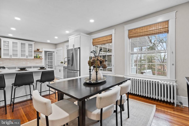 dining space with hardwood / wood-style floors and radiator heating unit