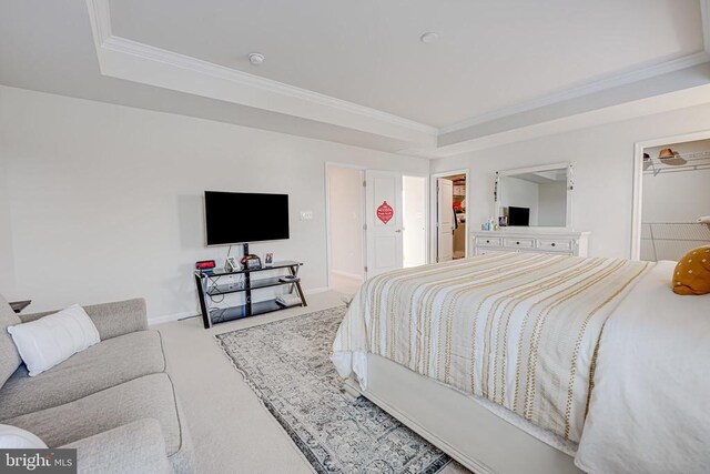 bedroom featuring carpet floors, a spacious closet, a tray ceiling, crown molding, and a closet