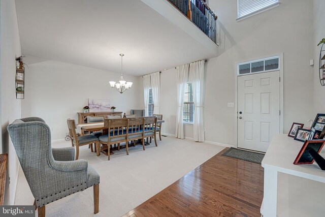 dining room with a towering ceiling, hardwood / wood-style floors, and a notable chandelier