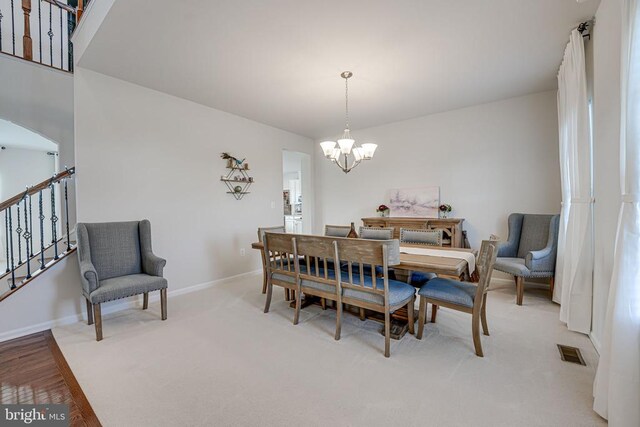 carpeted dining space with an inviting chandelier