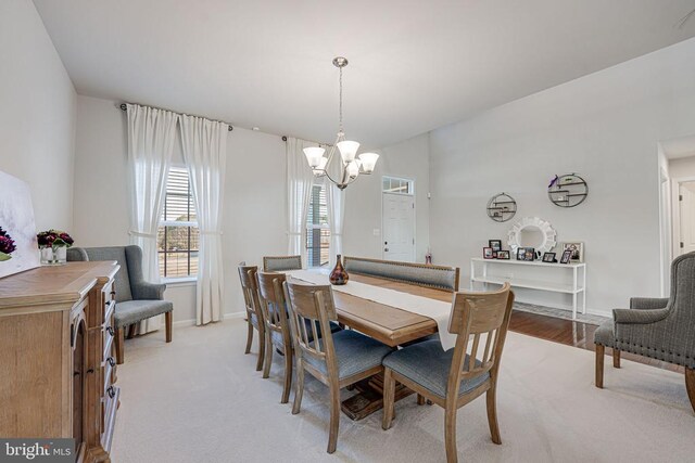 dining area featuring light carpet and a chandelier