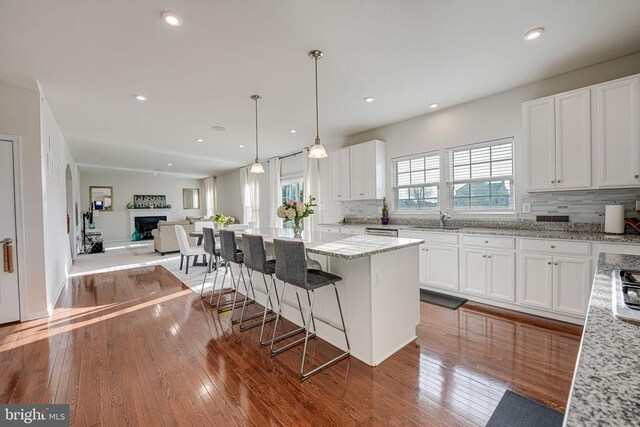 kitchen featuring white cabinetry, light stone counters, light hardwood / wood-style flooring, a kitchen island, and decorative backsplash