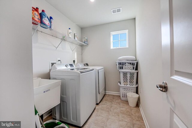 washroom with separate washer and dryer, sink, and light tile patterned flooring