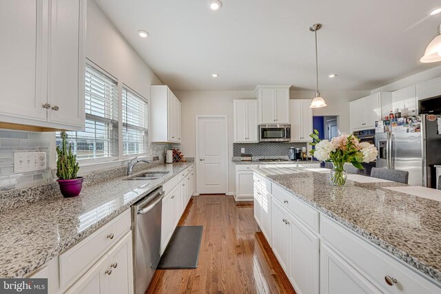 kitchen with white cabinetry, sink, decorative light fixtures, and appliances with stainless steel finishes