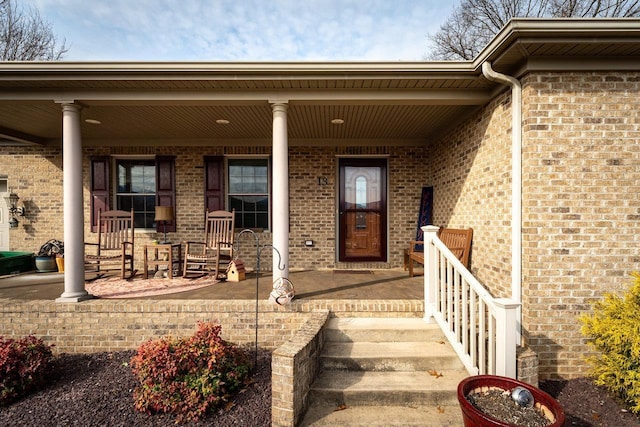 entrance to property with covered porch and brick siding