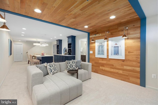 living room featuring light colored carpet, wooden walls, and wooden ceiling