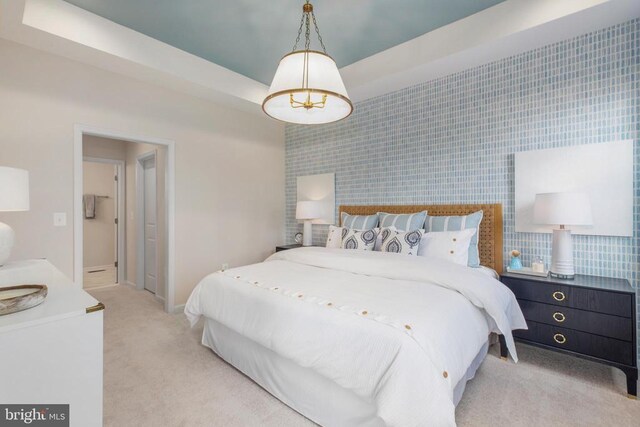 bedroom with light carpet and a raised ceiling