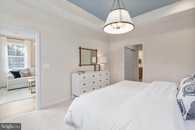 bedroom featuring a raised ceiling and light carpet