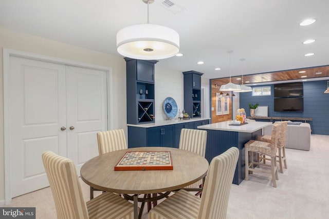 carpeted dining space featuring wood walls