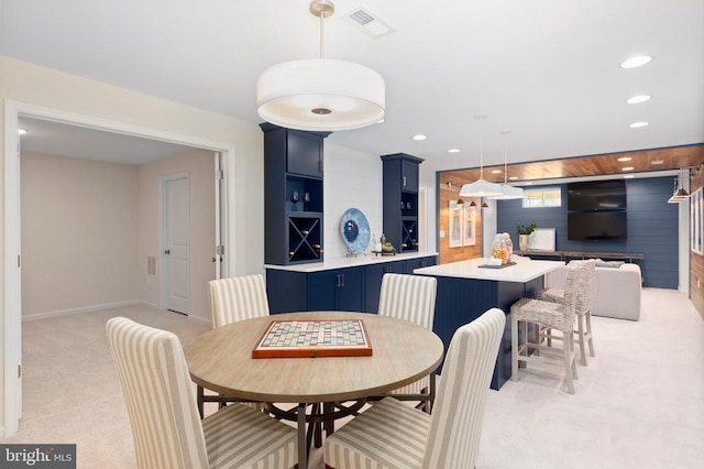 dining room with light carpet and wooden walls