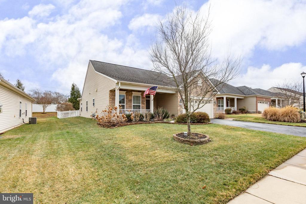 view of front of property with covered porch, fence, a garage, driveway, and a front lawn