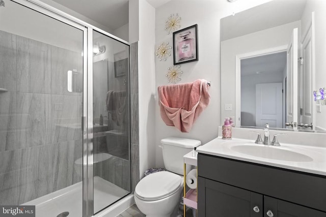 full bathroom featuring a stall shower, vanity, and toilet