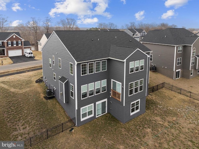 rear view of house featuring central AC, a shingled roof, fence, and a residential view