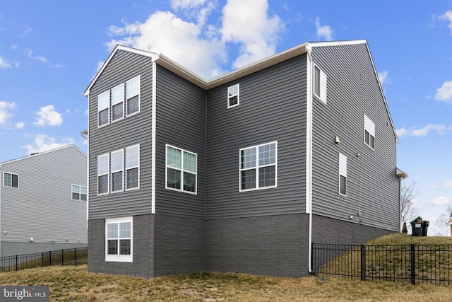 view of home's exterior with brick siding and fence