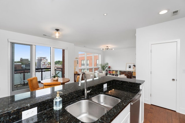 kitchen with a sink, dark stone counters, dark wood finished floors, white cabinetry, and dishwasher
