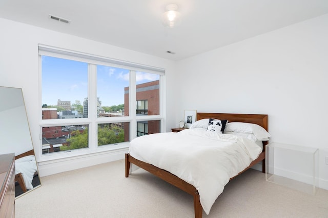 carpeted bedroom with a city view and visible vents
