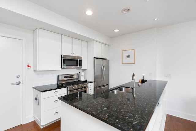 kitchen with a peninsula, dark wood-style flooring, stainless steel appliances, and a sink