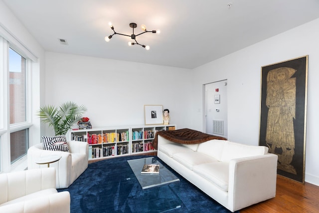 living room with an inviting chandelier, wood finished floors, and visible vents