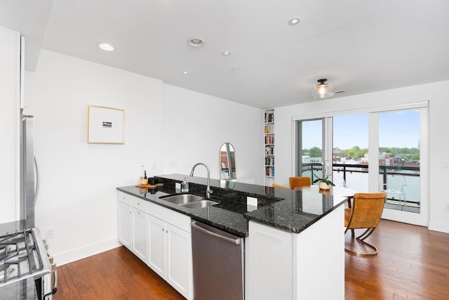 kitchen featuring dark wood finished floors, stainless steel appliances, a sink, a peninsula, and white cabinetry