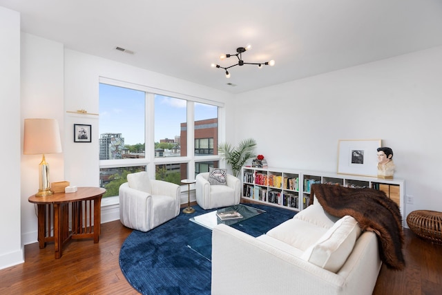 living area with wood finished floors, visible vents, and a notable chandelier