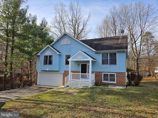 raised ranch featuring brick siding, a garage, a front yard, and driveway