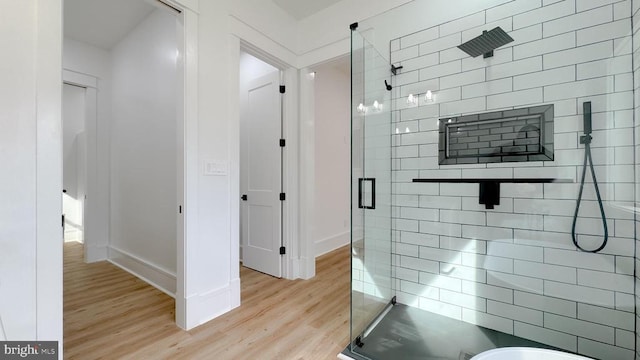 full bathroom featuring a stall shower, wood finished floors, and baseboards