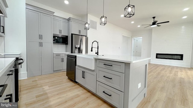 kitchen featuring a large fireplace, visible vents, gray cabinets, black appliances, and a sink