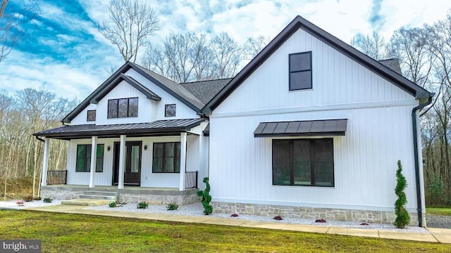 modern inspired farmhouse featuring covered porch, roof with shingles, a standing seam roof, and metal roof