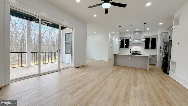 kitchen with hanging light fixtures, plenty of natural light, an island with sink, and refrigerator